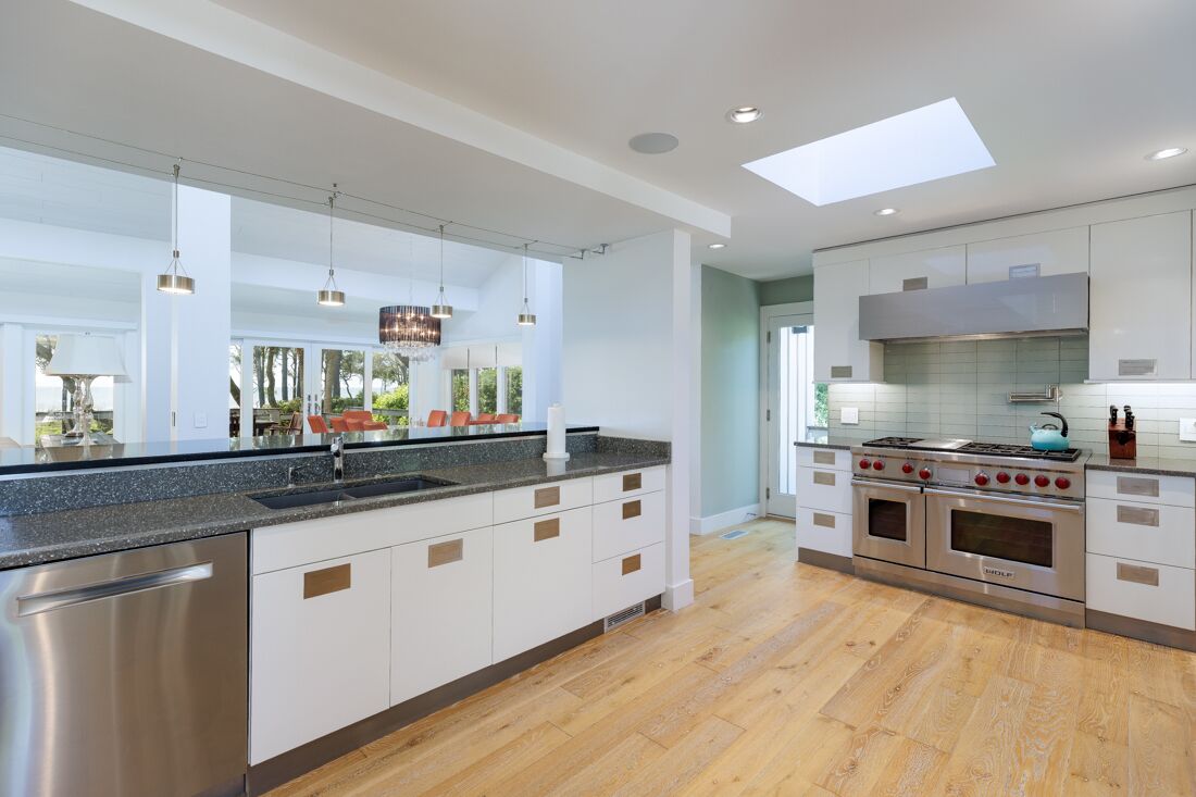 A modern kitchen with a central island, stainless steel appliances, and a skylight.