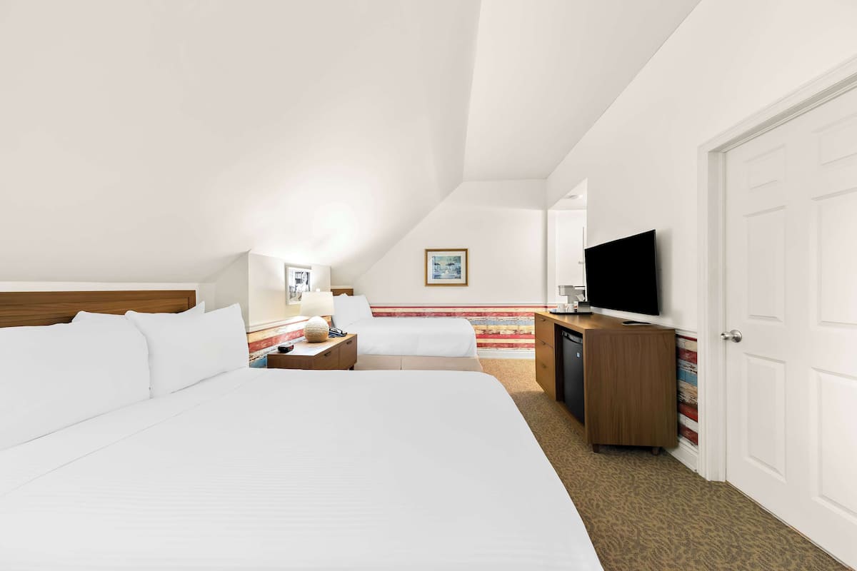 Una habitación de hotel con dos camas, televisión, escritorio y armario.