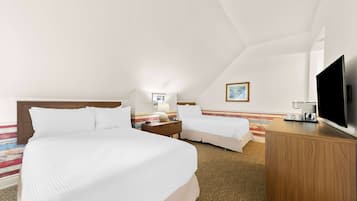 Habitación de hotel con dos camas, un televisor de pantalla plana, un aparador de madera y una mesita de noche con lámpara.