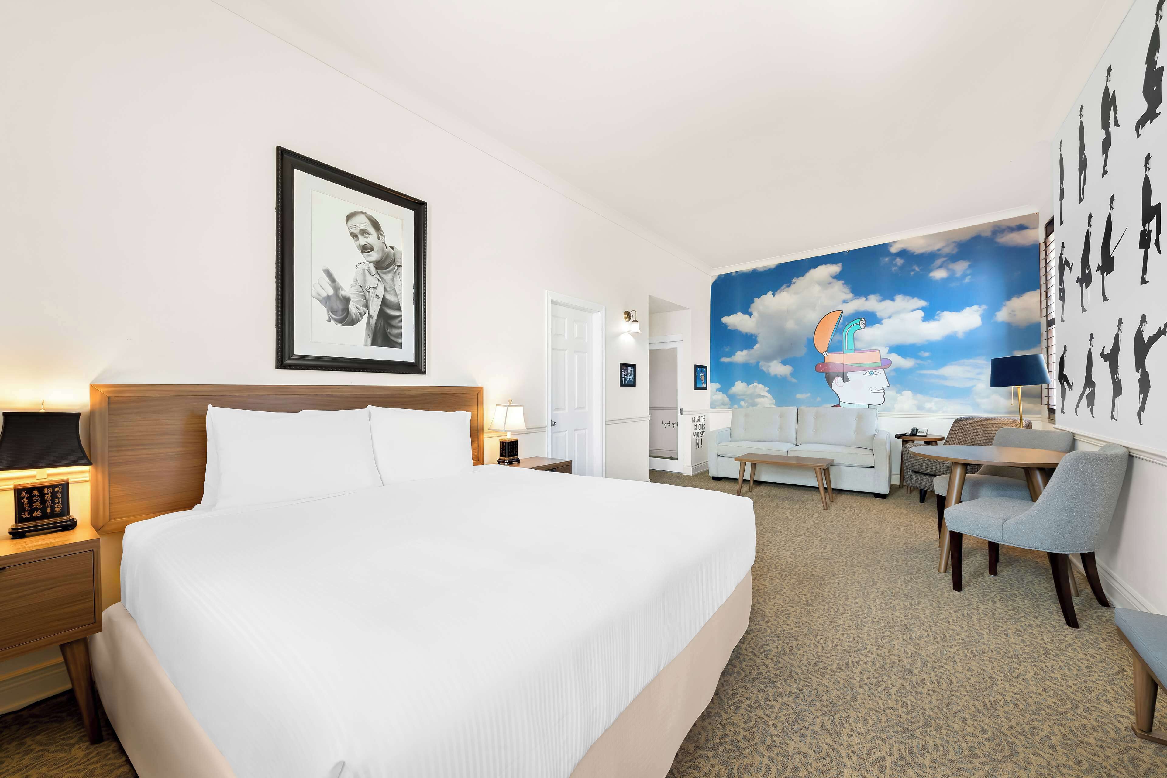 Une chambre d’hôtel avec un grand lit, un bureau, une chaise et une fresque murale.