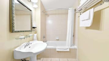 A bathroom with a white sink, a glass shelf, a shower with a glass door, and a towel rack.
