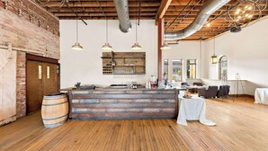 Un espace bar au style rustique, avec un plancher en bois, un comptoir et des luminaires suspendus.