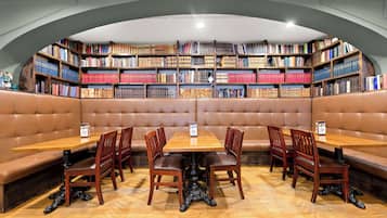 A library-style seating area with bookshelves, a wooden table, and leather benches.
