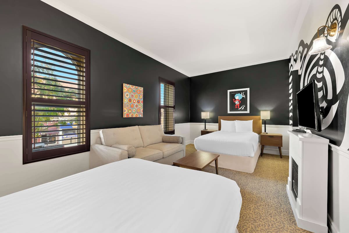 Habitación de hotel con una cama grande, un sofá, un escritorio y un televisor.