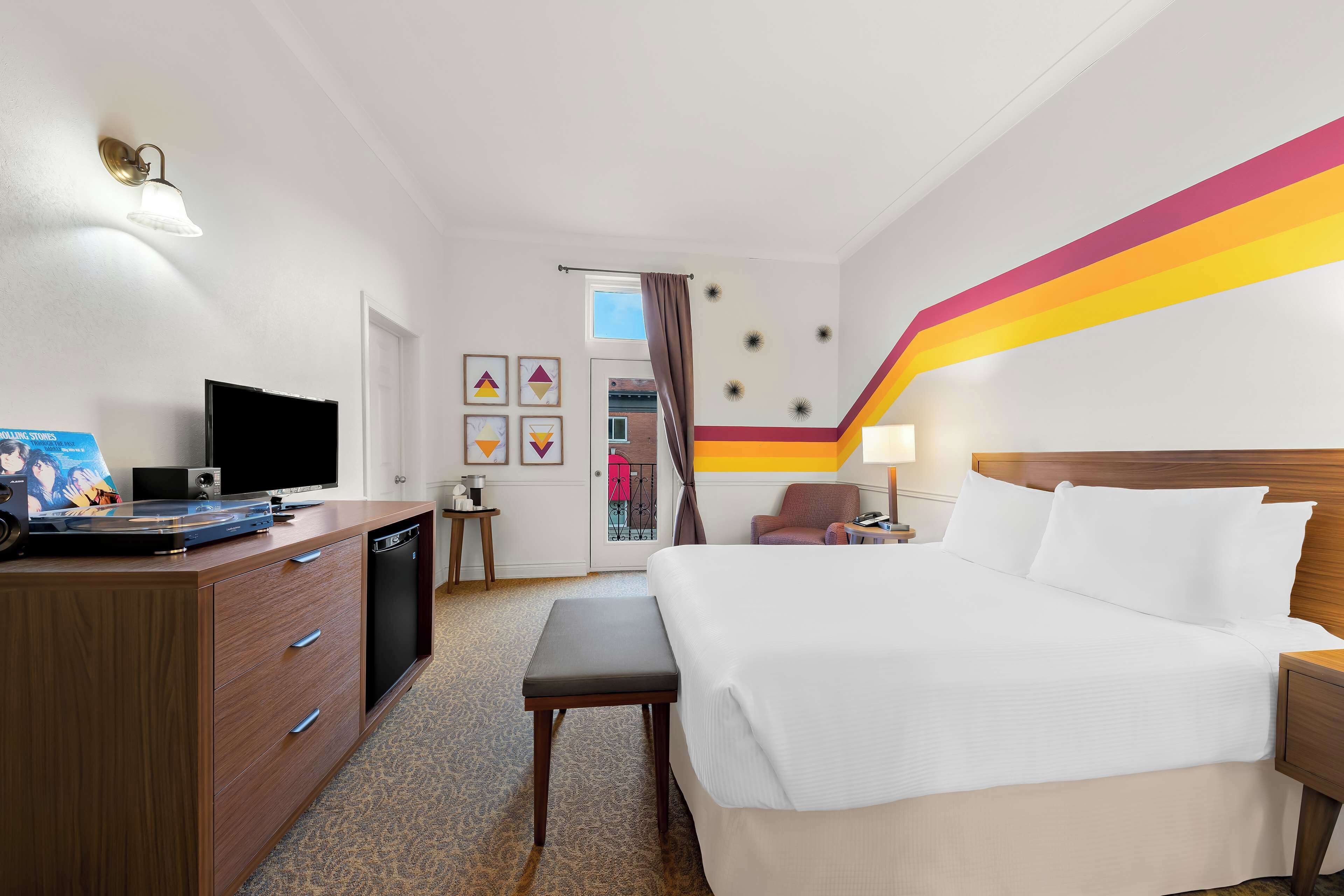 Une chambre d’hôtel équipée d’un lit, d’une table de chevet, d’une lampe, d’une télévision et d’un bureau avec un ordinateur.