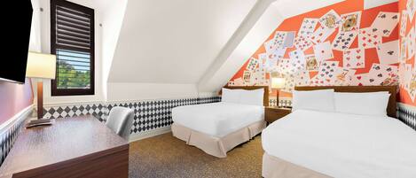 A hotel room with two beds, a desk, and a patterned carpet.