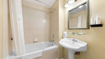 A bathroom with a bathtub, a sink, a mirror, and a shelf with toiletries.