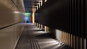 A corridor with a patterned floor, a wall with vertical slats, and a door at the end.