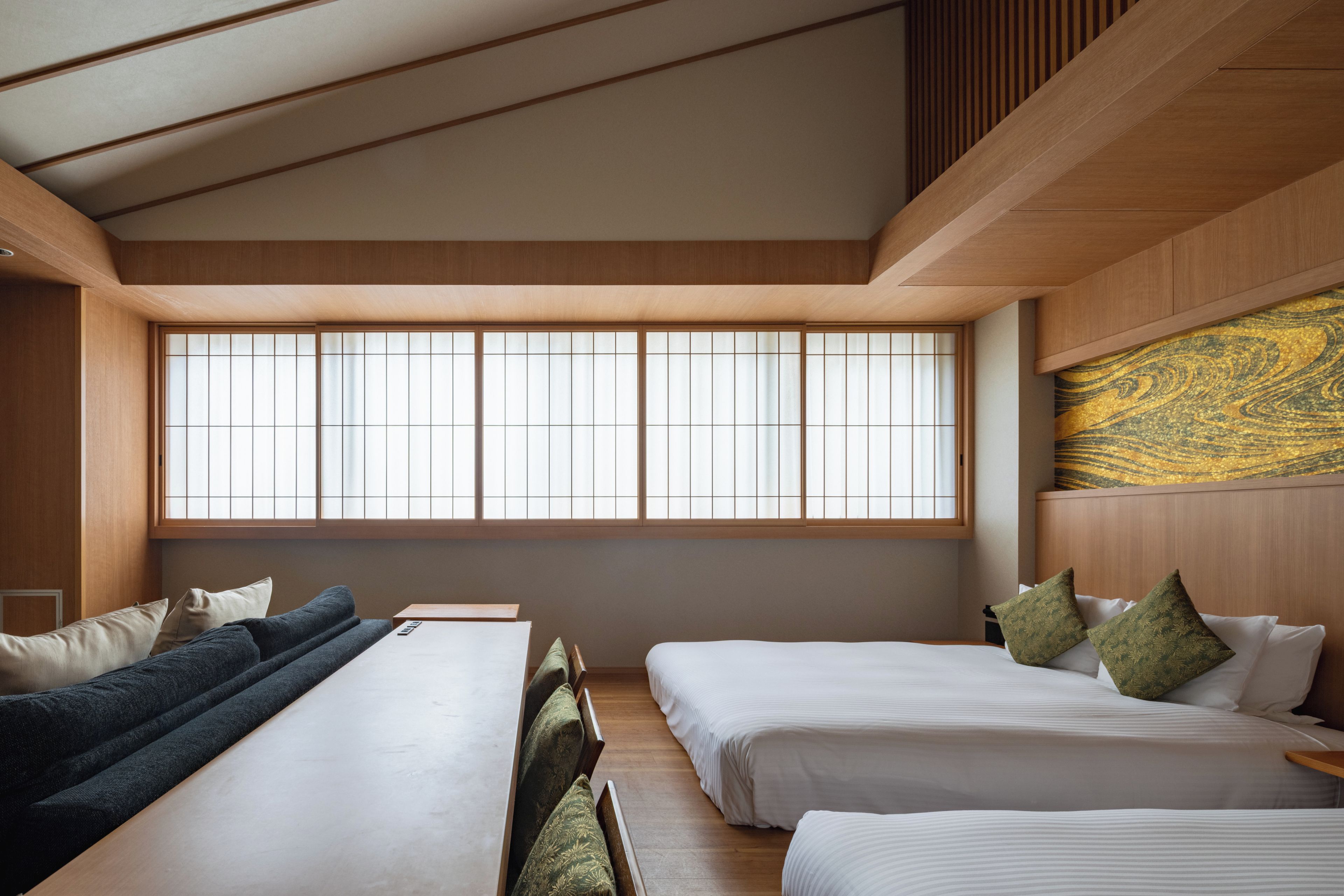 A hotel room with a large window, two beds, a sofa, and a wooden ceiling.