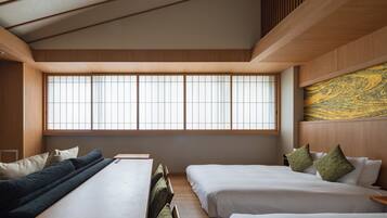 A hotel room with a large window, two beds, a sofa, and a wooden ceiling.