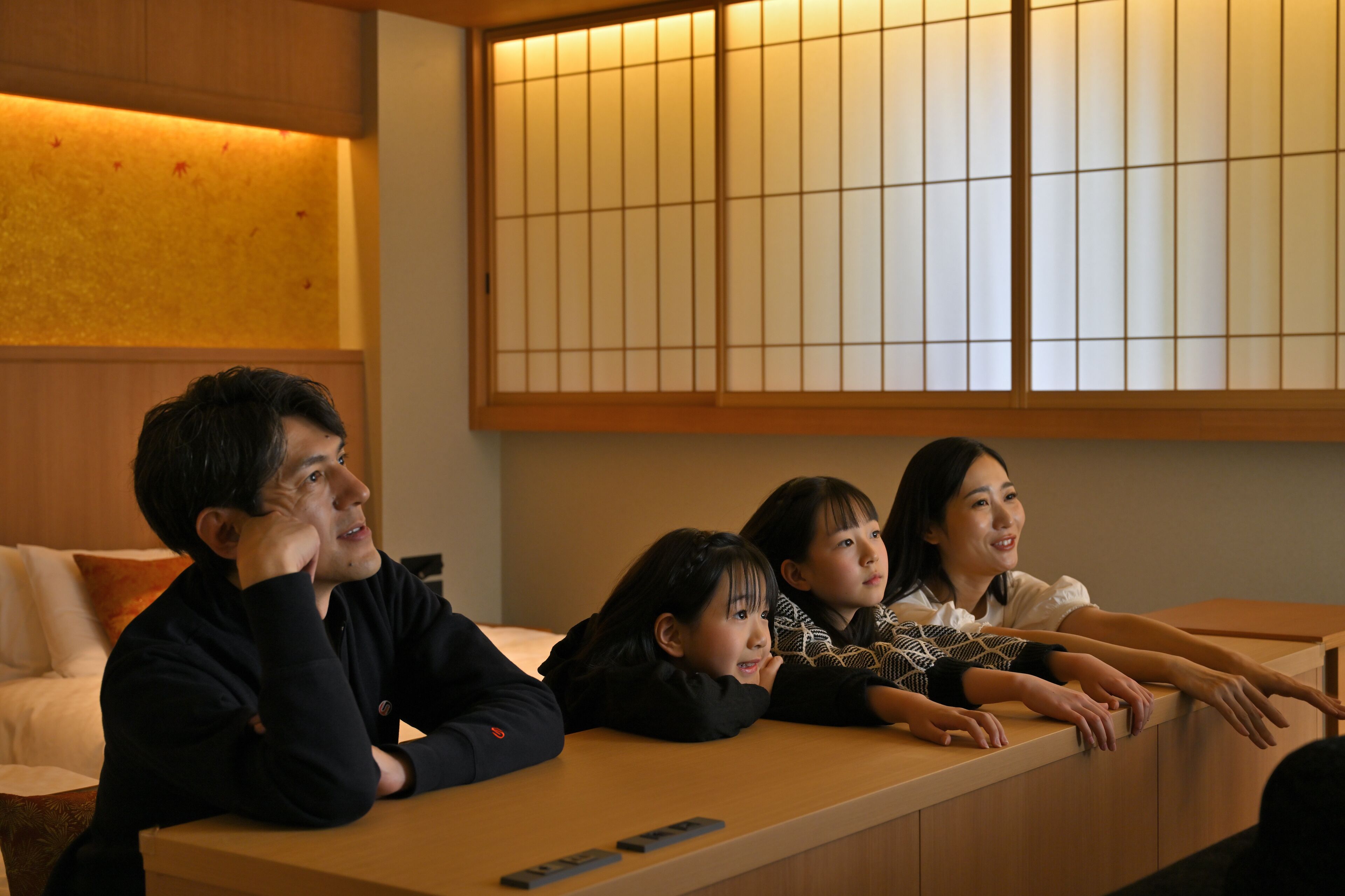 Une pièce avec un bureau en bois, un canapé et un paravent japonais traditionnel en papier.