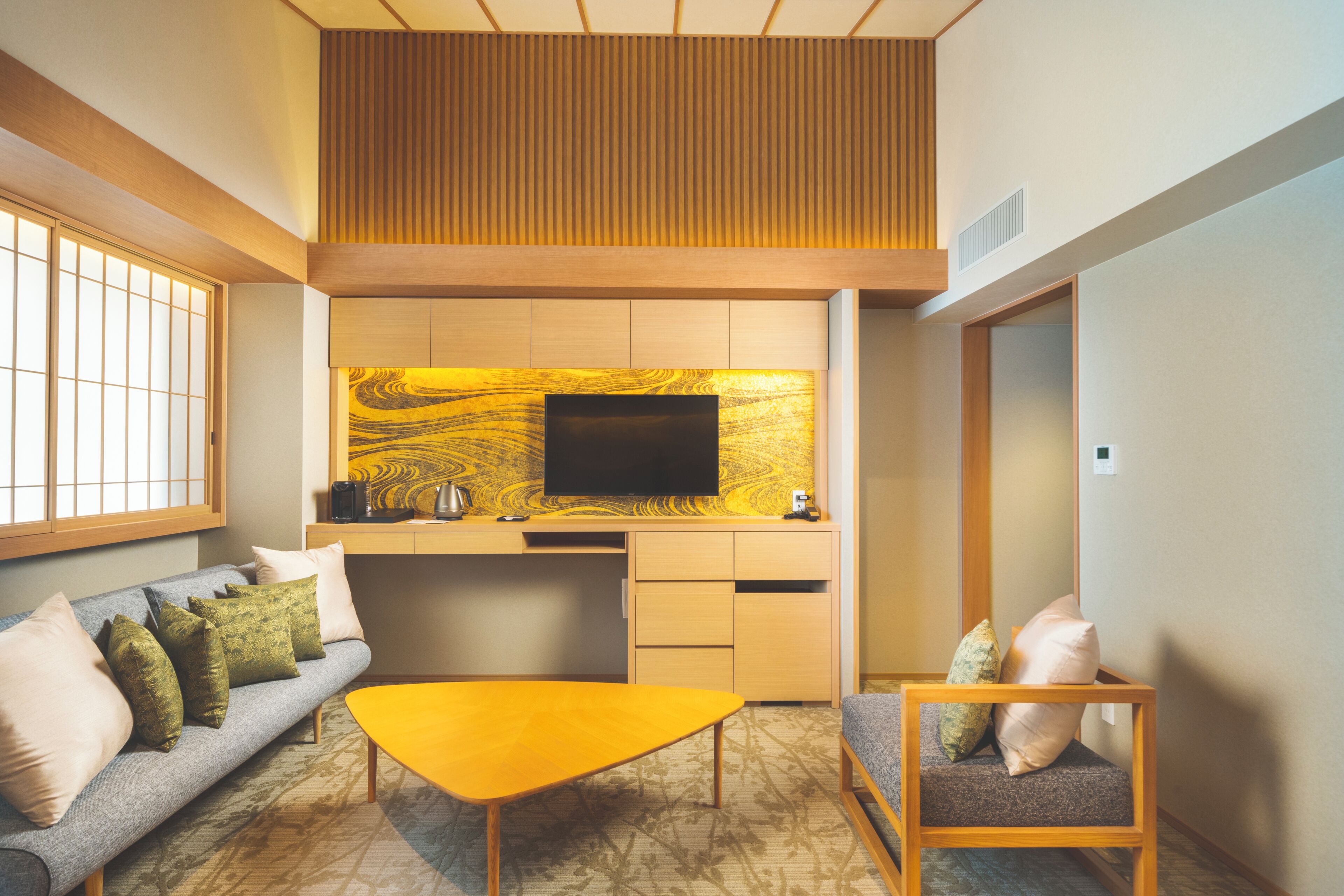 Ein modernes Interieur mit einer Couch, einem gelben Tisch, einem Fernseher und einer Küchenzeile.