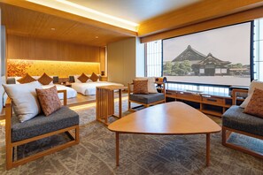 A hotel room with a traditional Japanese-style bed, a wooden desk, and a large window offering a view of a historical building.