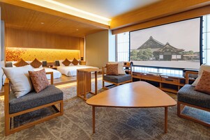 Ein Hotelzimmer mit einem traditionellen japanischen Bett, einem Holztisch und einem großen Fenster mit Blick auf ein historisches Gebäude.