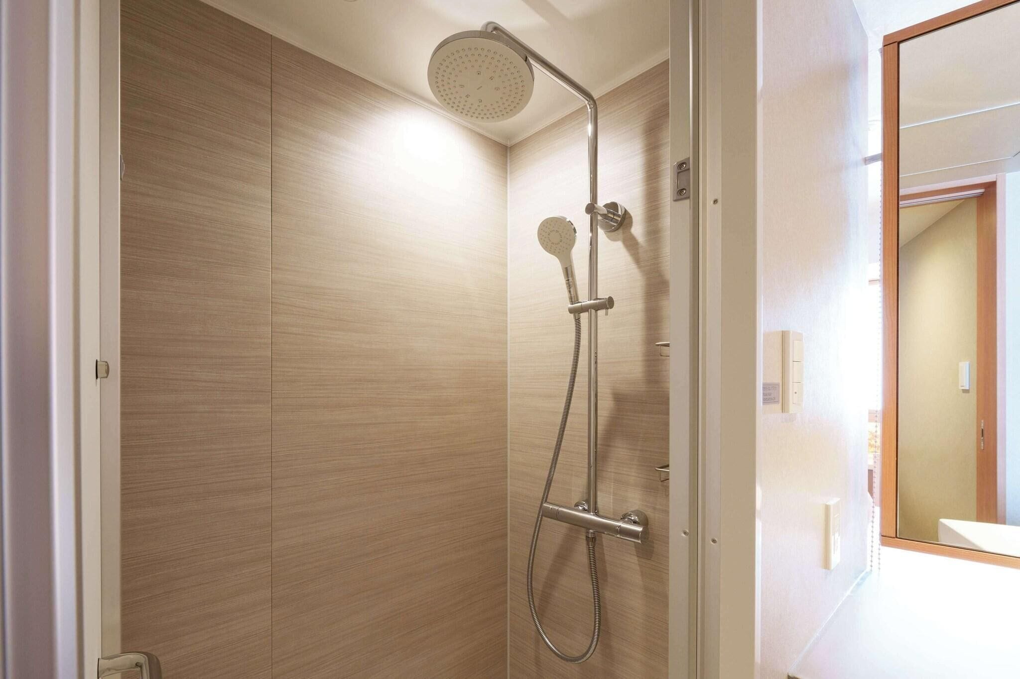 Une douche moderne équipée d’un pommeau de douche à main et d’un pommeau de douche fixe au plafond.