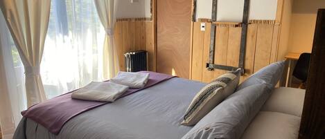 Un dormitorio con cama, radiador, paneles de madera y cabecero de metal rústico.