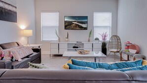 Una sala de estar moderna con un sofá, una mesa de centro y un televisor montado en la pared.