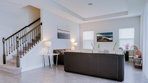 Un amplio salón con una escalera, un sofá, una mesa de centro y un comedor.
