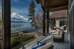 Une terrasse couverte, aménagée avec du mobilier d’extérieur, donnant sur un lac.