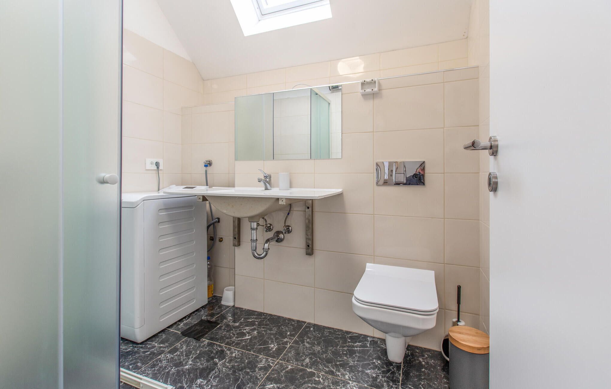 Een badkamer met een wit toilet, een wastafel met een spiegel erboven en een douchecel.