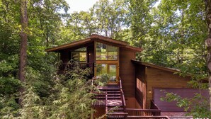 Eine Holzhütte mit Balkon und Garage, umgeben von dichtem Wald.