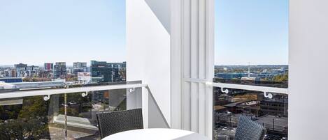 Un balcon avec une table blanche et des chaises en osier, offrant une vue sur la ville.