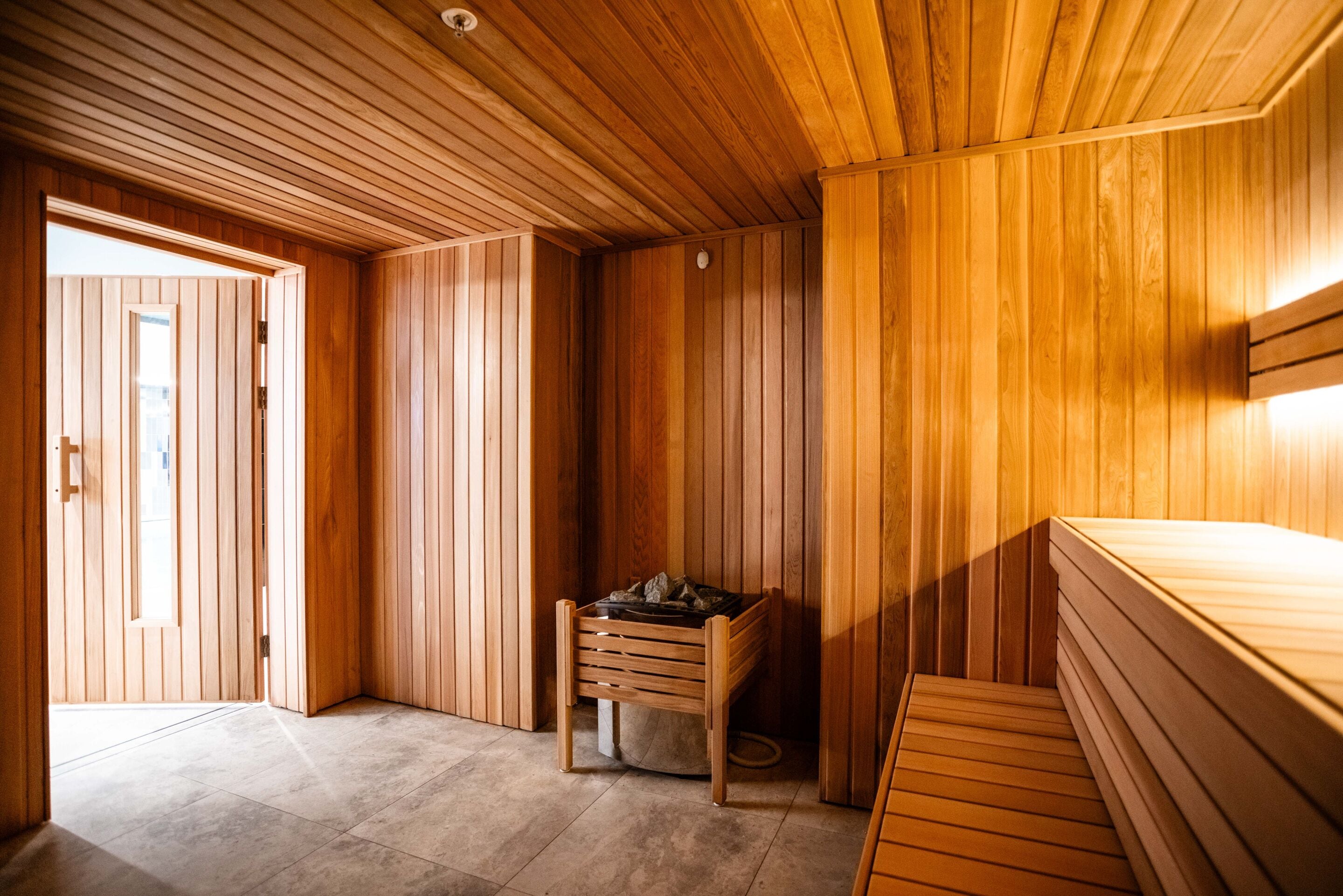 A wooden sauna room with a bench and a small table.