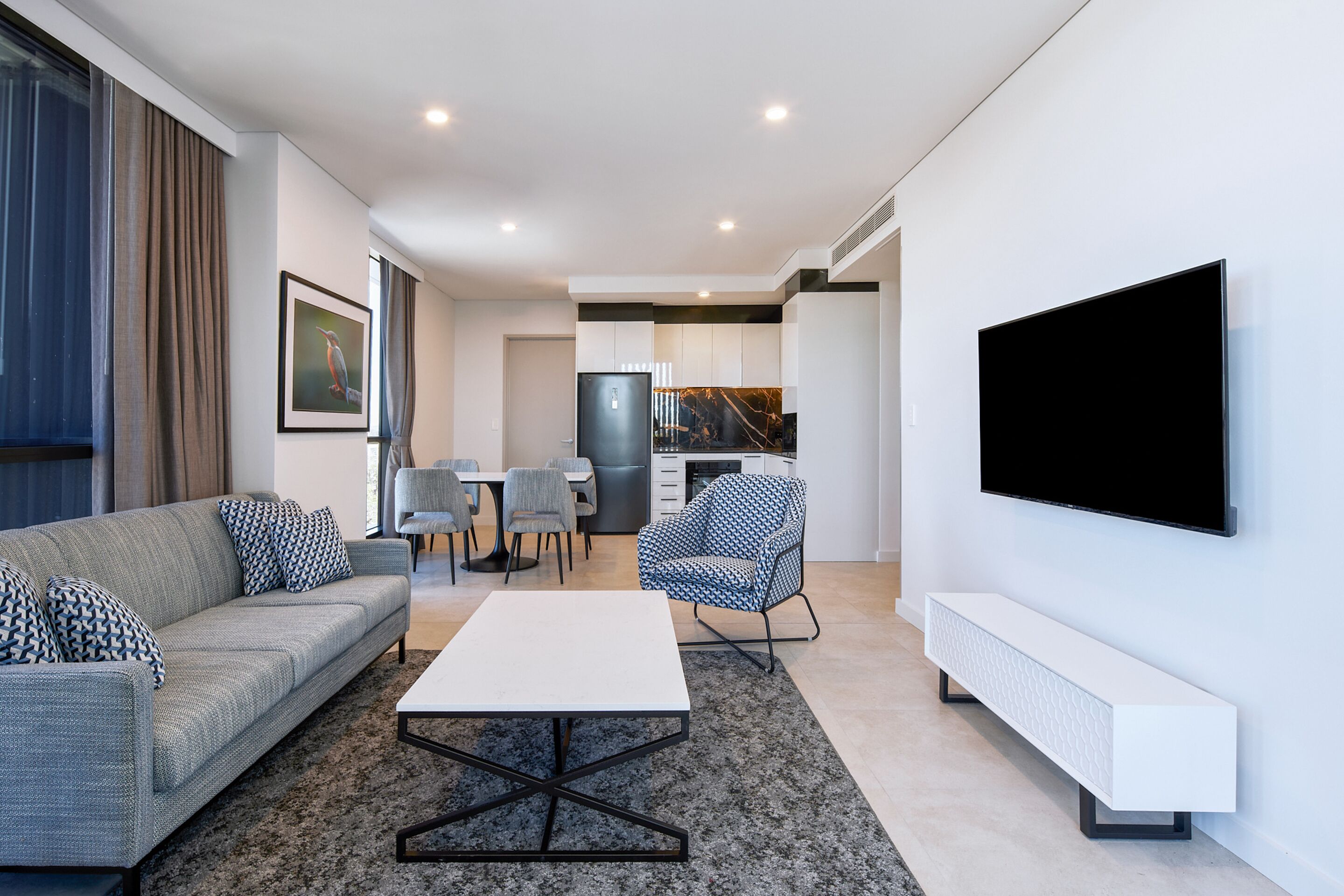 A modern living room with a sofa, coffee table, and a flat-screen TV mounted on the wall.