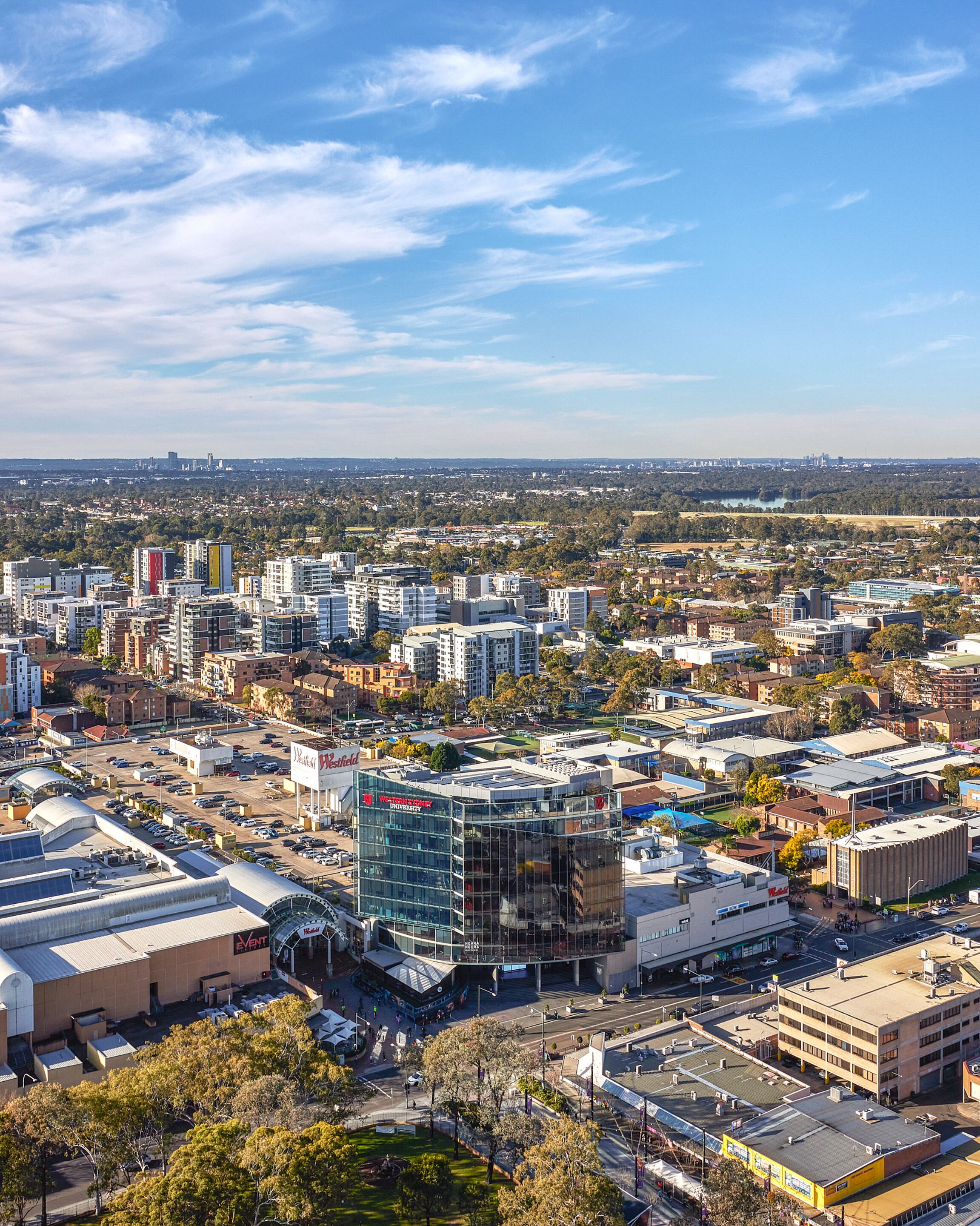 A cityscape with a mix of modern and older buildings, a prominent Western Sydney Institute building, and a view of the surrounding urban area.