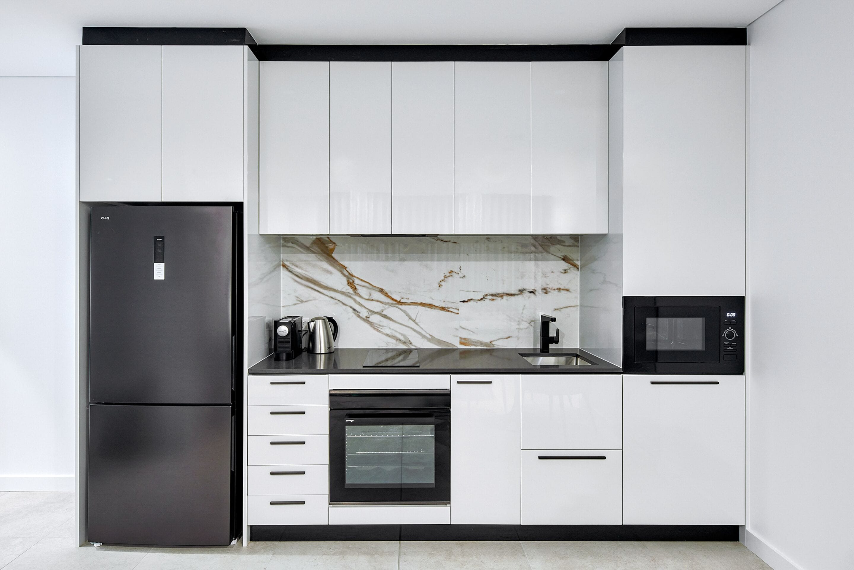 A modern kitchen with a built-in oven, a microwave, and a refrigerator.