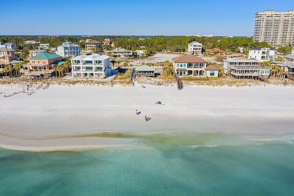A coastal residential area with beachfront properties, clear skies, and a sandy beach.