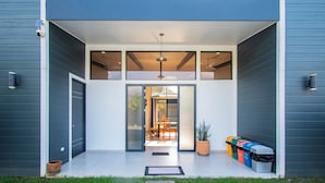 A modern house with a large glass door leading to a dining area.