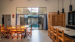A spacious dining area with a pool view, wooden furniture, and modern lighting.