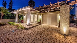 A modern house with a covered patio, a garage, and a well-lit entrance. - Mermaids Oasis | Private Pool, Hot Tub, & 5 Minute Walk to St. Armands Circle & Lido Key Beach! (Lido Key)