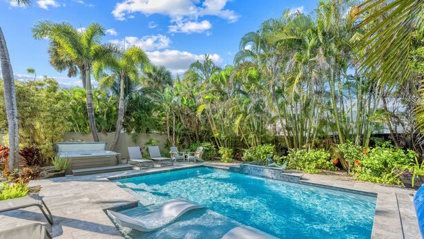 A swimming pool with lounge chairs and a hot tub, surrounded by palm trees and tropical plants. - Mermaids Oasis | Private Pool, Hot Tub, & 5 Minute Walk to St. Armands Circle & Lido Key Beach! (Lido Key)