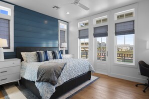 A bedroom with a bed, nightstands, a desk, and a chair. - Game Room, Resort Pools, Golf Cart Boardwalk to the Beach (Port Aransas)