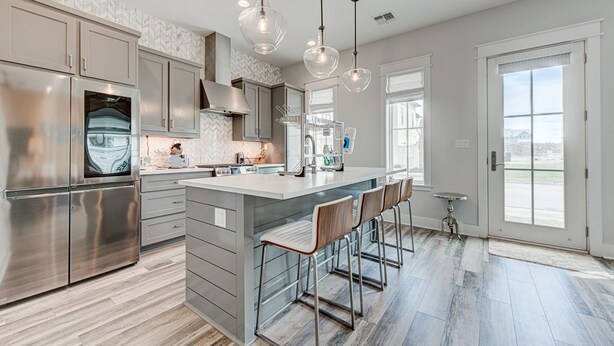 A modern kitchen with stainless steel appliances, a large island with bar stools, pendant lighting, and large windows. - Resort Pools, Golf Cart Boardwalk to Beach, Pet Friendly (Port Aransas)
