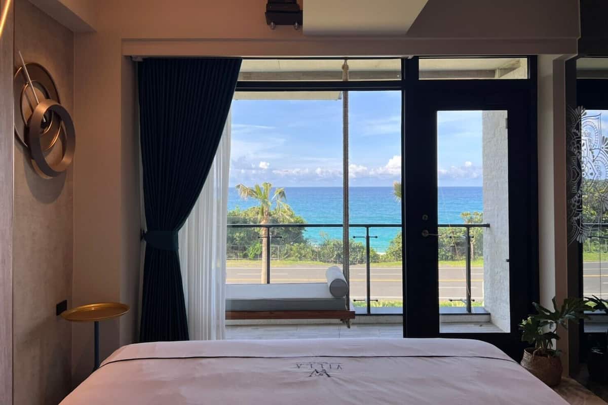 A bedroom with a large window offering a view of the ocean.