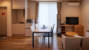 Una habitación de hotel moderna con comedor, kitchenette y televisor.