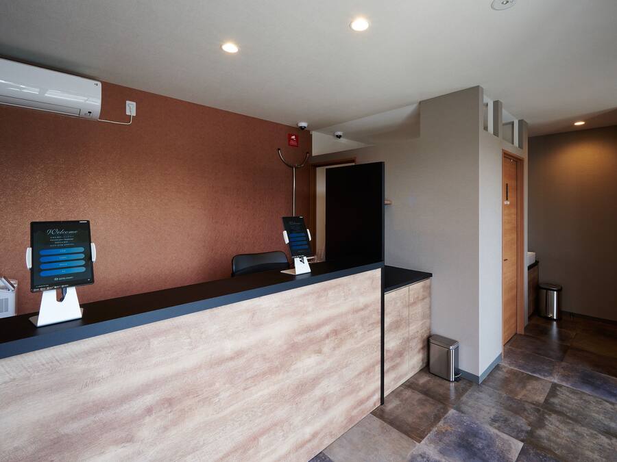 A reception desk with a digital screen, a trash bin, and a door to a room.