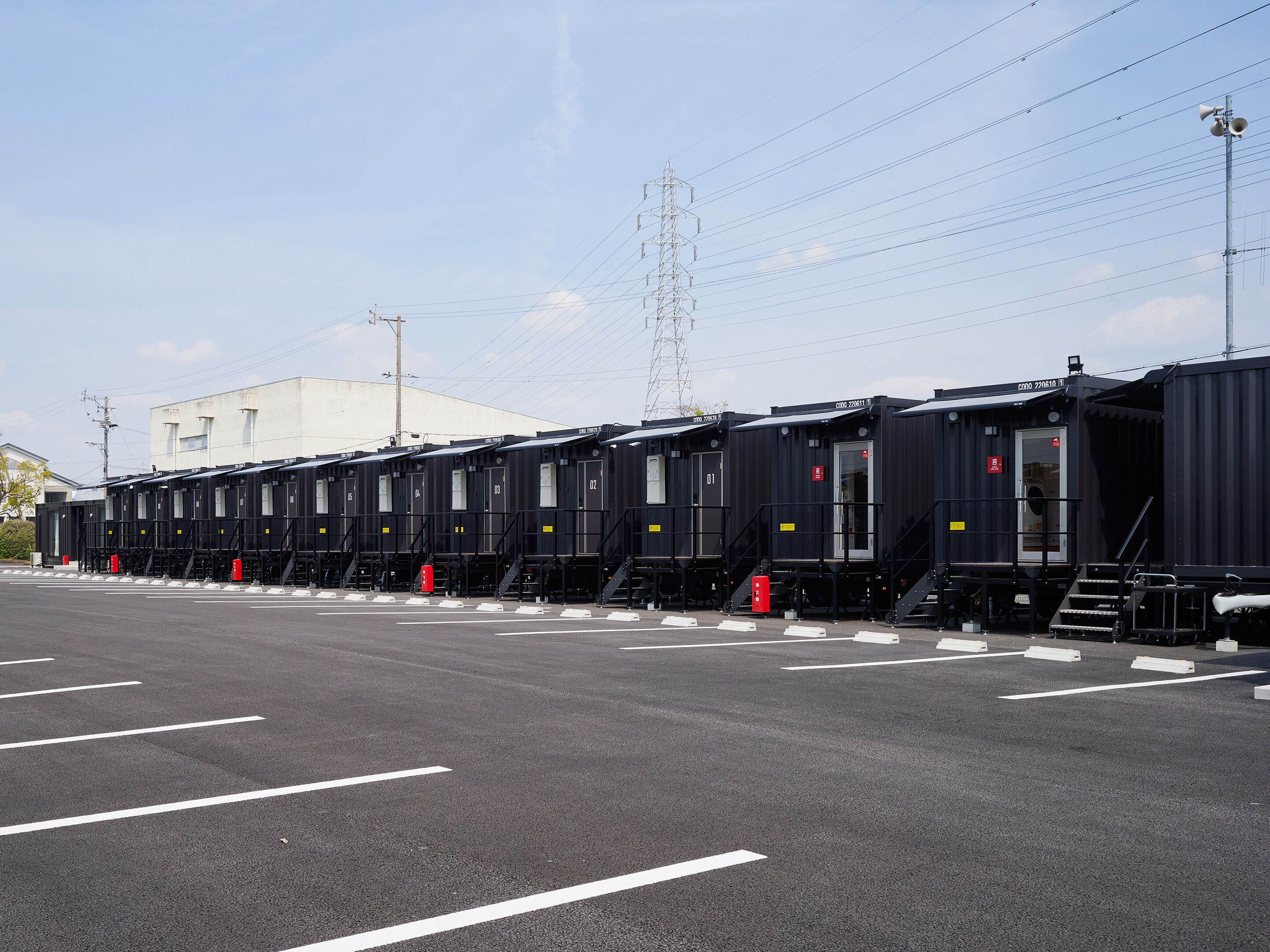A row of black train carriages parked in a lot with white lines on the ground.