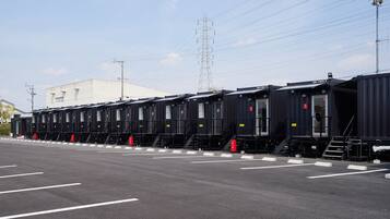 A row of black train carriages parked in a lot with white lines on the ground.