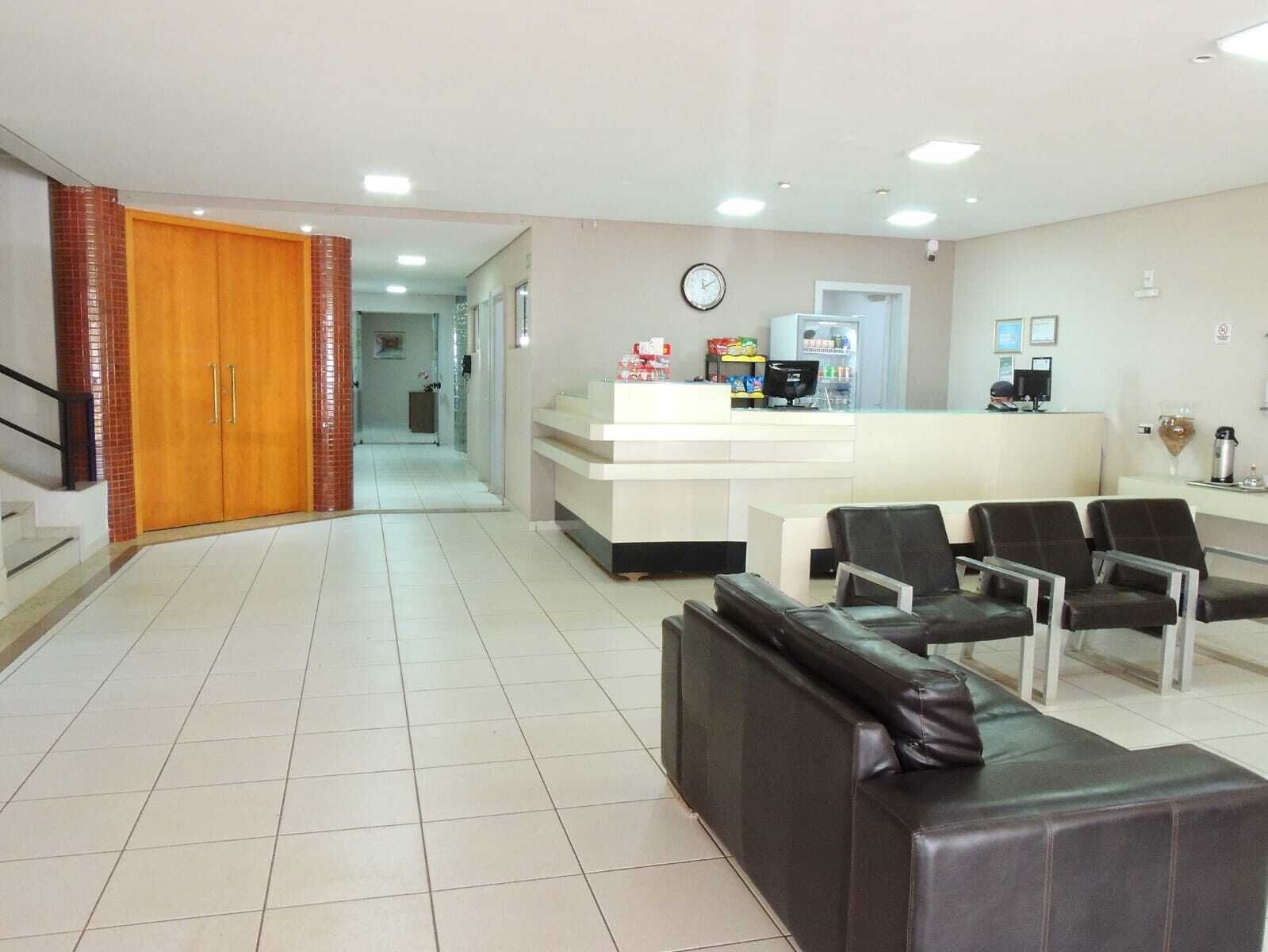 A reception area with a counter, chairs, a clock, and a staircase leading to another room.