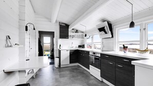 Una cocina moderna con armarios blancos y oscuros, horno empotrado y un amplio ventanal con vistas.