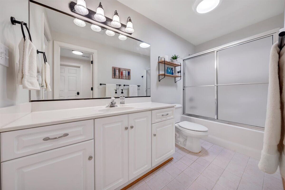 Une salle de bain moderne avec un meuble-lavabo blanc, un grand miroir et une cabine de douche.