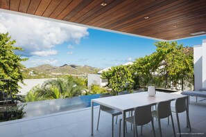 Un espace de restauration extérieur moderne, doté d’une piscine et offrant une vue sur un paysage montagneux.