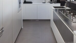 A modern kitchen with white cabinetry, a large window, and a skylight.