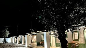 A row of rooms with a covered outdoor area, a tree, and a table with chairs.