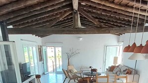 A spacious living area with a wooden dining table, comfortable seating, and a view of the outdoors.