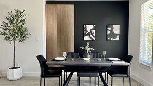 A modern dining area with a dark wooden table, black chairs, and a potted plant. - Scenic Retreat W/ Playground & Grilling (Granbury)